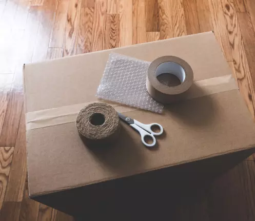 Packing tape, scissors, and bubble wrap on a sealed cardboard box for moving at Storage Star.