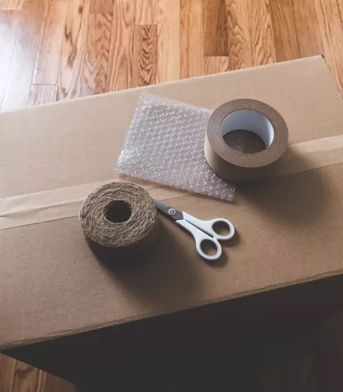 Packing tape, scissors, and bubble wrap on a sealed cardboard box for moving at Storage Star.